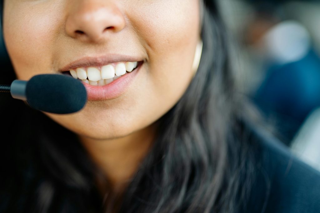 pexels-photo-8867207-8867207 Close-up of a smiling customer service agent wearing a headset in an office environment.